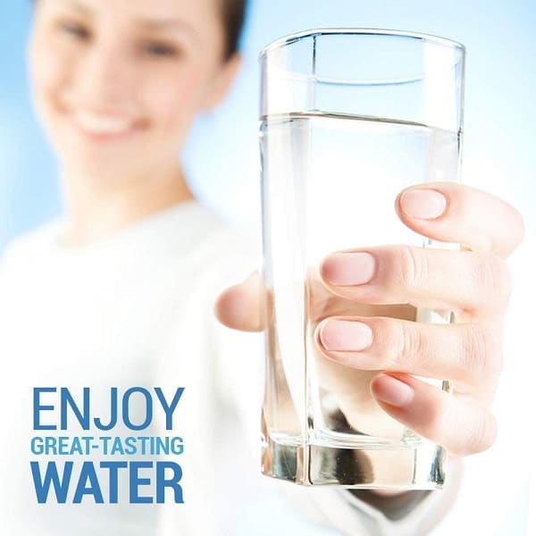 A newly filtered glass of water held by a smiling woman