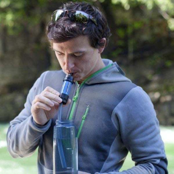 A man sipping water from his Sawyer Mini water filter