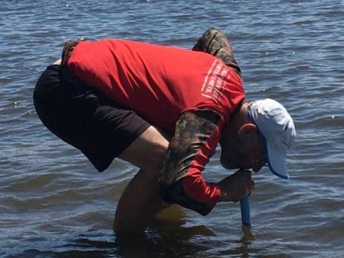 man drinking water from the lake using lifestraw personal