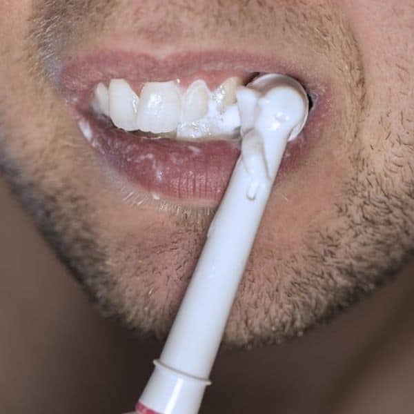 man brushing teeth with dental fluorosis risk